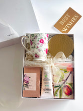 Load image into Gallery viewer, Luxury gift hamper by Grande Gift Hampers featuring a floral mug and dark chocolate, brass coaster, fragrance wax bar and hand cream.