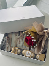 Load image into Gallery viewer, Personalised couple gift hamper by Grande Gift Hampers featuring a custom photo frame, faux red roses, chocolate, and message bottle.
